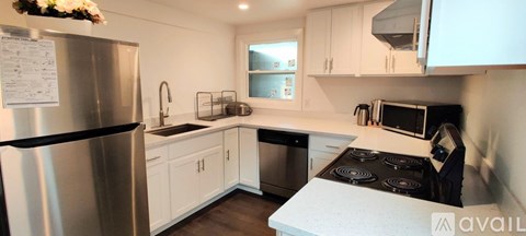 A kitchen with white cabinets and a stainless steel refrigerator.