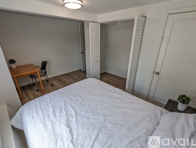 A bedroom with a bed, desk, and chair.