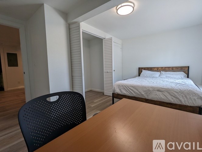 A bedroom with a bed, chair, and table.