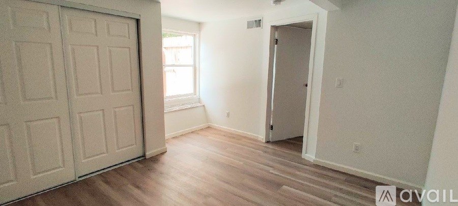 A room with a white door and a window with sunlight coming through.