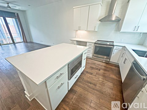 A kitchen with white cabinets and a wooden floor.