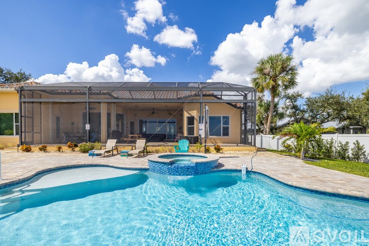 A swimming pool in front of a house with a patio and a pool table.