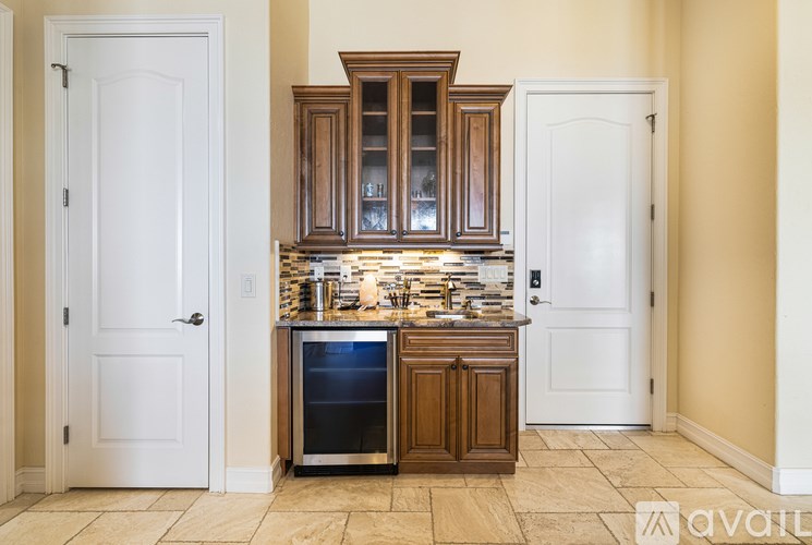 A kitchen with a white door, a brown cabinet, and a tiled floor.