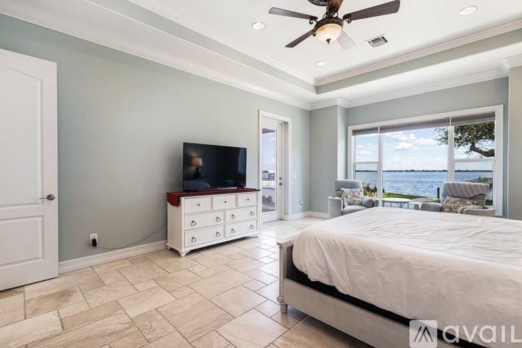 A bedroom with a large bed, a television, and a ceiling fan.