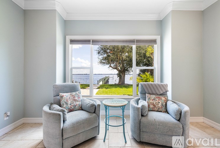Two grey couches and a table in a room with a view of the outdoors.