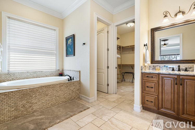 A bathroom with a tub, sink, and mirror.