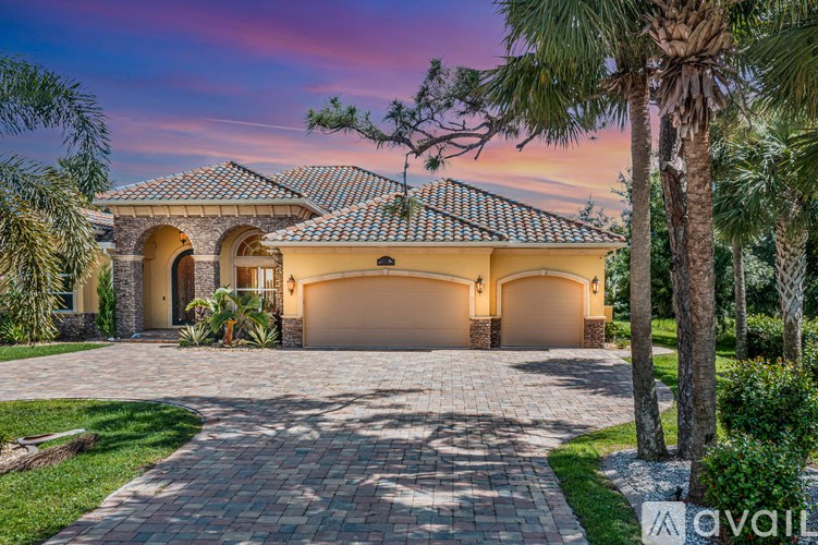 A house with a driveway and palm trees in front.