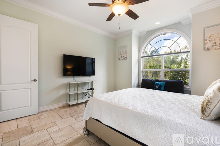 A bedroom with a bed, a television, and a ceiling fan.