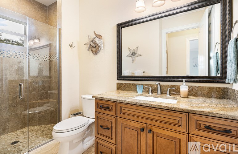 A bathroom with a toilet, sink, and mirror.