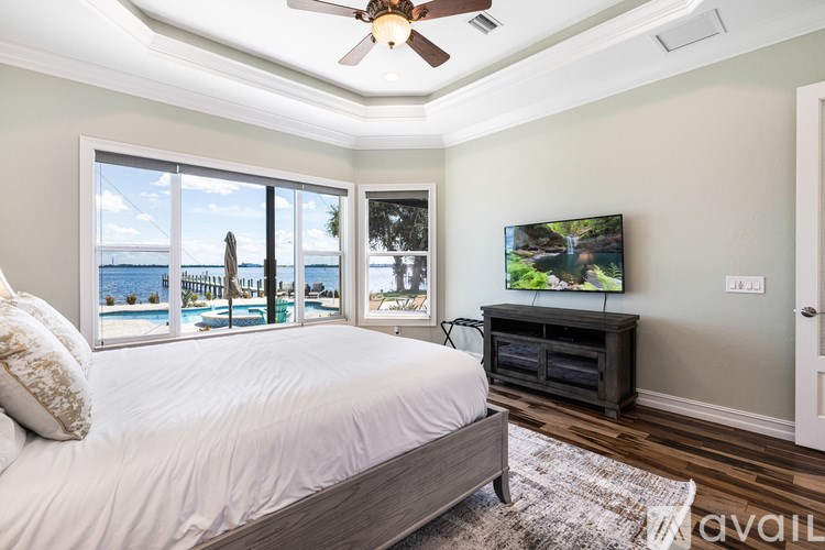 A bedroom with a bed, a ceiling fan, and a television.