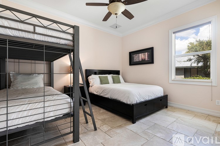 A bedroom with a bed, a chair, and a ceiling fan.