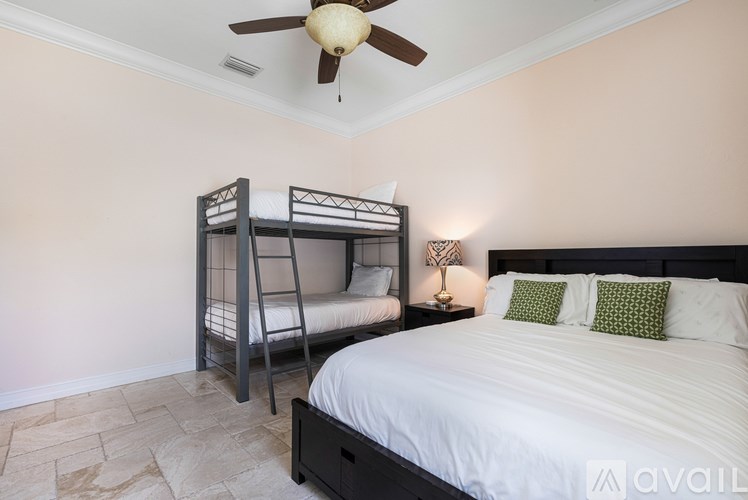 A bedroom with a white bed and a bunk bed with a ceiling fan.
