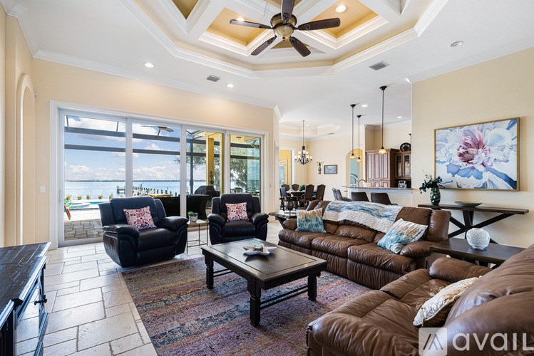A living room with a ceiling fan and a view of the beach.