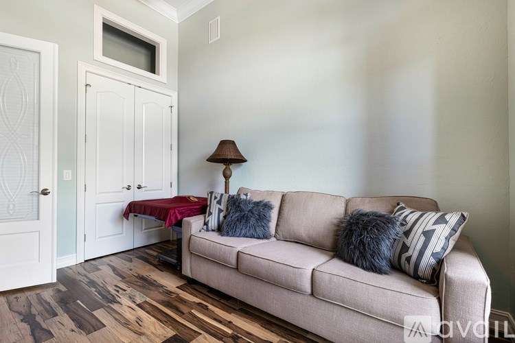 A living room with a couch, a lamp, and a table with a red cloth on it.