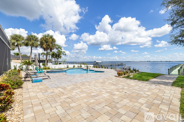 A patio with a pool and palm trees in the background.