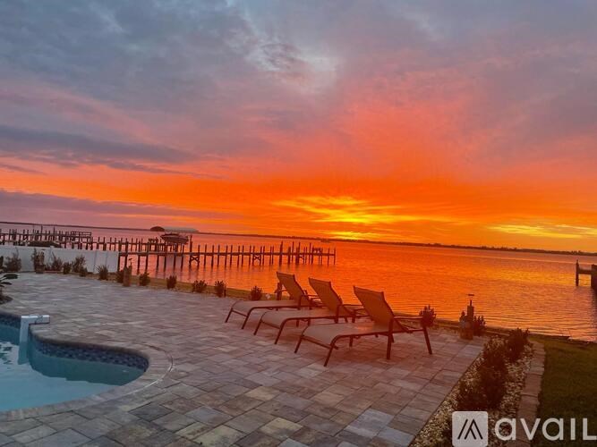 A sunset view with a pool and chairs.