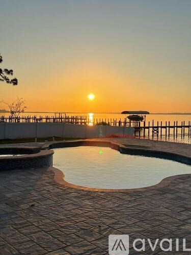 A sunset view with a pool and a pavilion.
