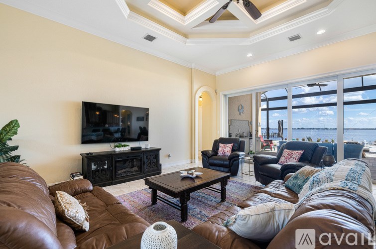 A living room with a brown leather couch and a flat screen TV mounted on the wall.