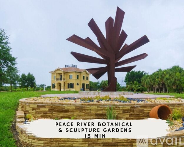 A sign for Peace River Botanical & Sculpture Gardens is in front of a yellow building.