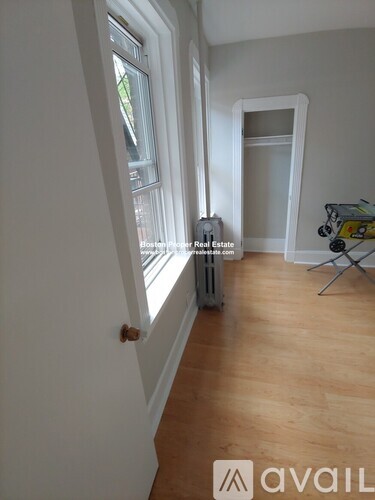 A room with a window and a wooden floor.