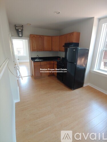 A kitchen with wooden cabinets and a black refrigerator.