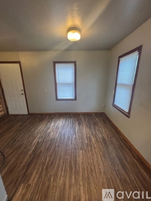 A room with wooden flooring and a window with blinds.