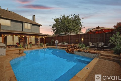 A swimming pool in a backyard with a house and a fence.