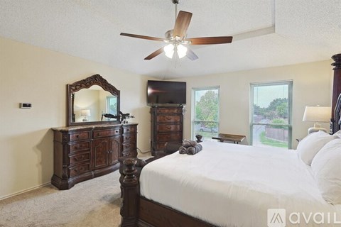 A bedroom with a large bed, a dresser with a mirror, and a ceiling fan.