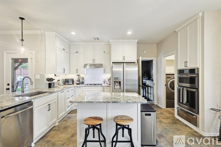 A kitchen with white cabinets and a marble countertop.