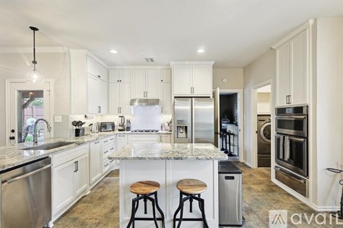 A kitchen with white cabinets and a marble countertop.