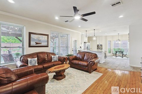 A living room with brown leather furniture and a ceiling fan.