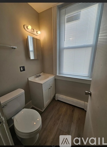 A bathroom with a toilet, sink, and mirror.