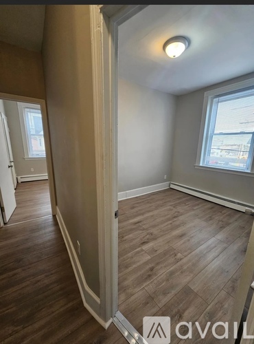 A room with wooden flooring and a window showing a view of buildings outside.
