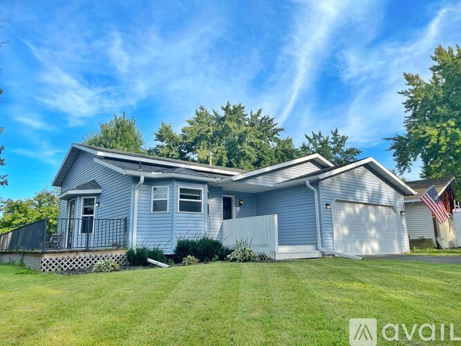 A house with a blue exterior and a garage door is for sale.