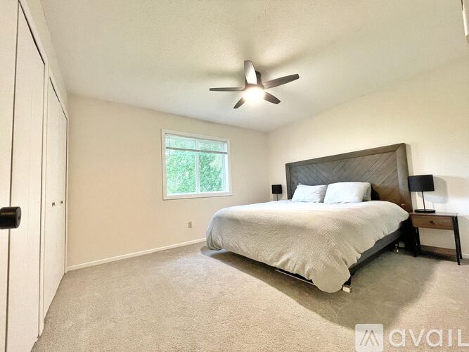 A bedroom with a bed, a ceiling fan, and a window.