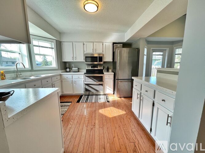 A kitchen with white cabinets and a wooden floor.