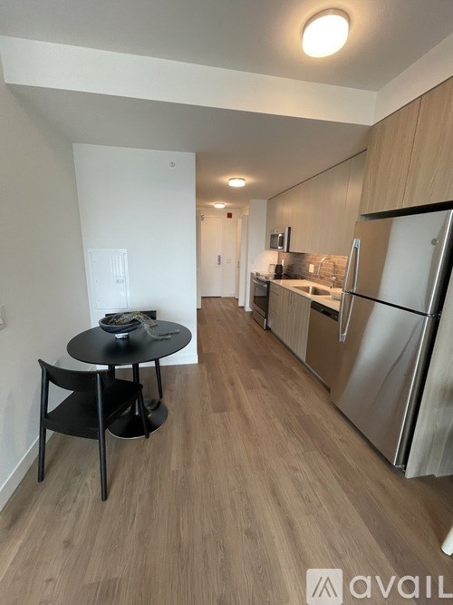 A kitchen with a table and chairs in the foreground and a refrigerator in the background.