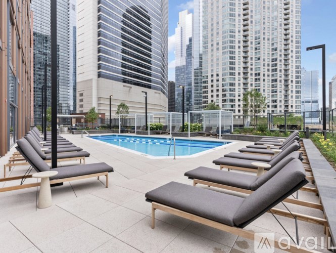 A poolside lounge area with black cushioned sun loungers.