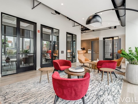 A modern living room with red chairs and a large window.
