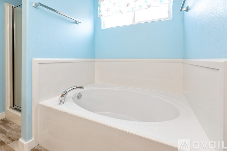 A white bathtub with a silver faucet is in a bathroom with blue walls.