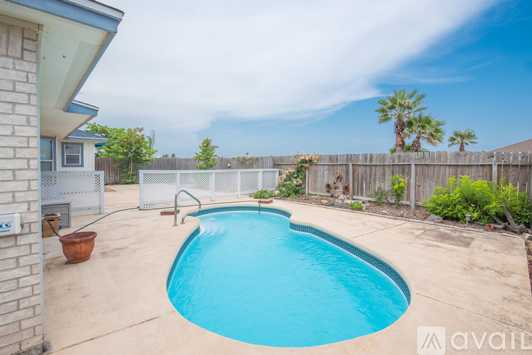 A backyard with a blue pool and a wooden fence.