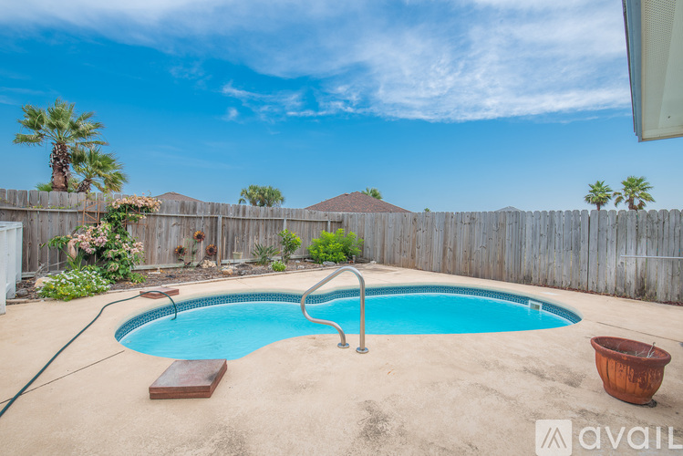 A small pool in a backyard with a wooden bench and a hose.