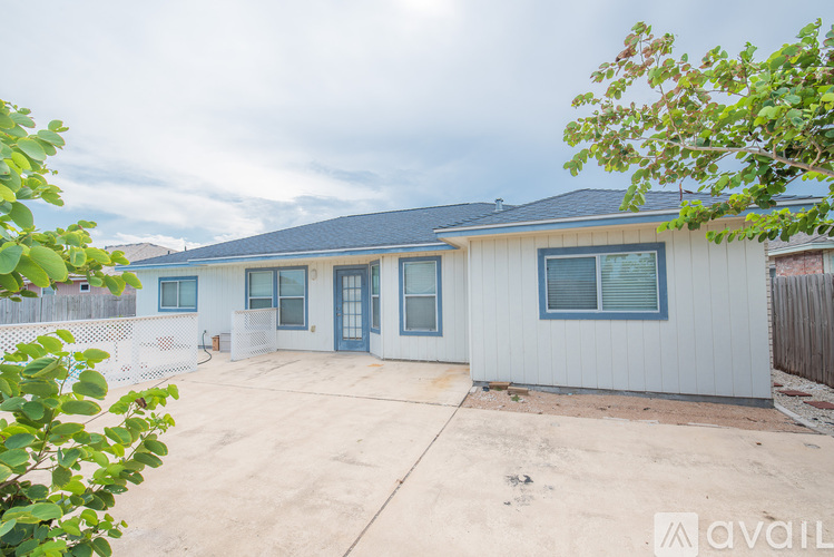 A house with a grey siding and a white fence is available for rent.