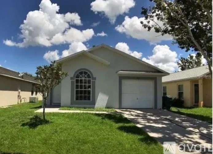 A house with a white garage door and a tree in front.