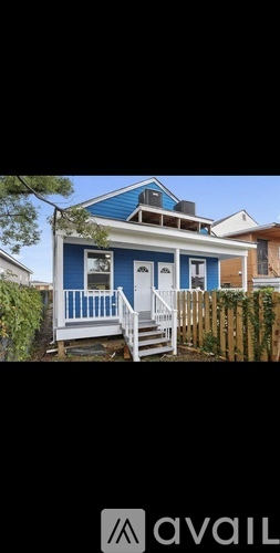 A blue house with white railings and a white porch.
