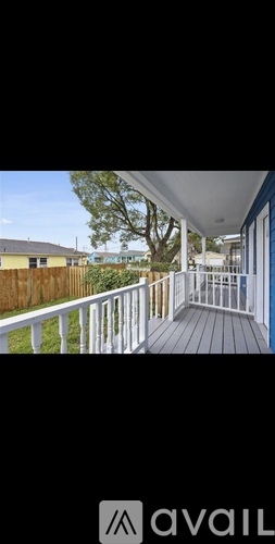 A balcony with a white railing and a view of a backyard.