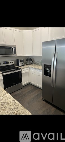 A kitchen with white cabinets and a stainless steel refrigerator.
