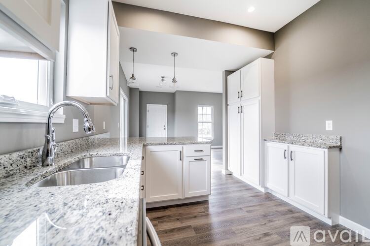 A kitchen with a marble countertop and white cabinets.
