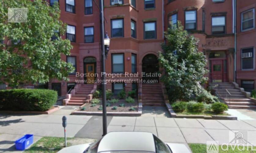 A red brick building with a tree in front of it.