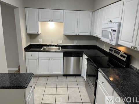 A kitchen with white cabinets and black countertops.